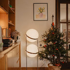 Decorative indoor Christmas tree with lights and ornaments in a room with a lamp and framed picture on the wall.