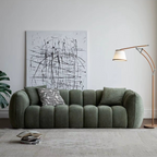 Green sofa in a living room with abstract art and a lamp.