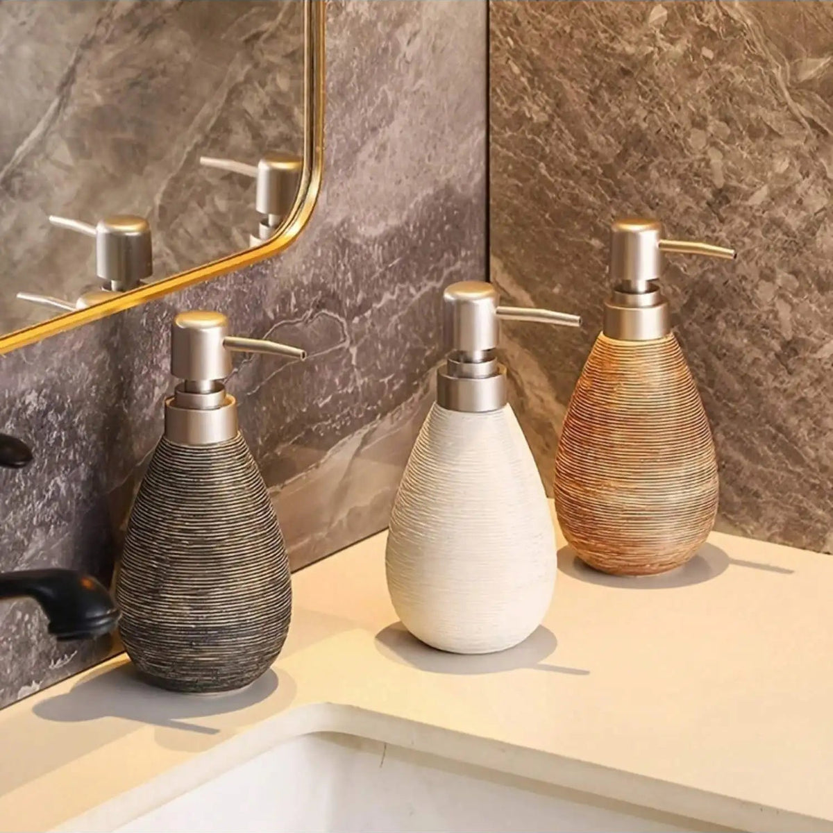 Three decorative soap dispensers on a bathroom counter with a mirror in the background.
