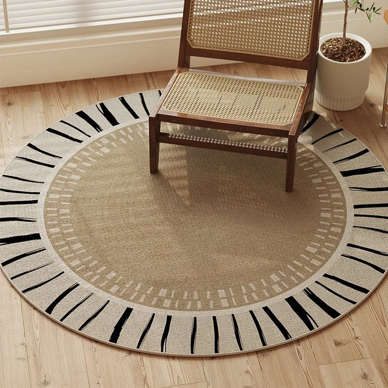 Round rug with black and white pattern on a wooden floor, chair placed on it.