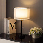 Table lamp on a reflective surface with books and flowers in the background
