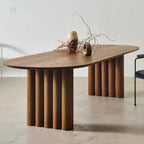 Wooden dining table with a minimalist design on a light floor.
