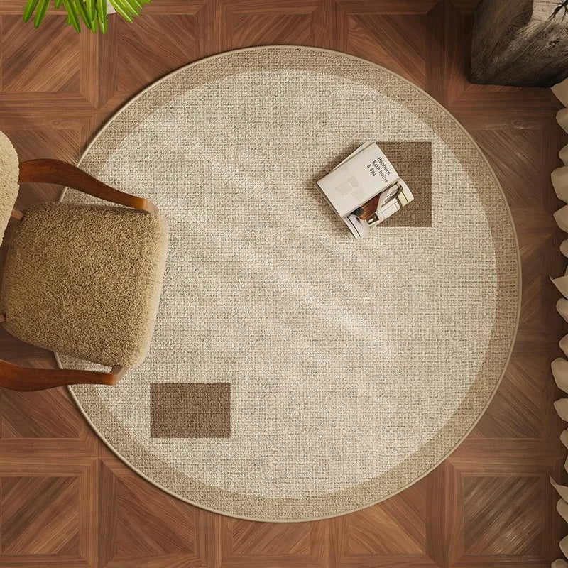 Round beige rug on a wooden floor with a chair and books on top