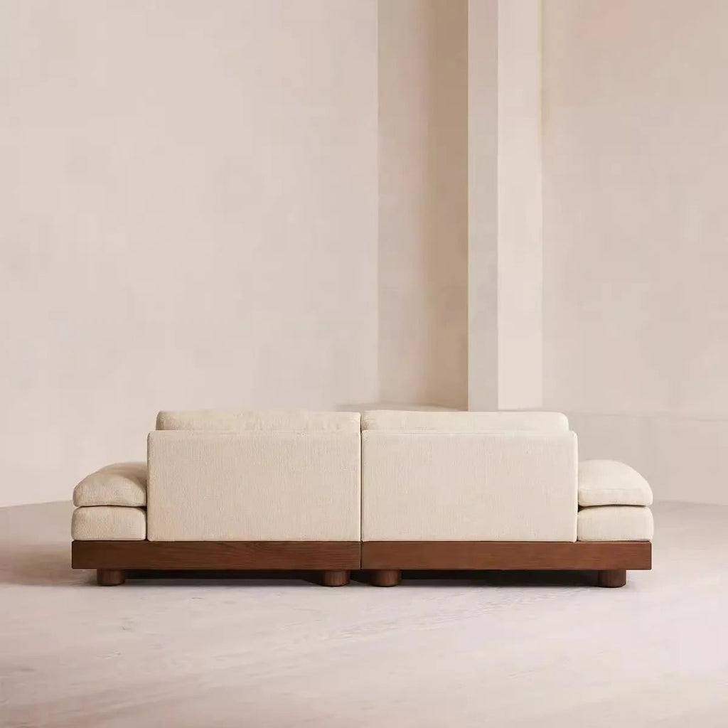 Modern white sofa with wooden base against a plain wall