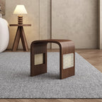Wooden side table with geometric design on a gray rug in a room with a lamp and wall.