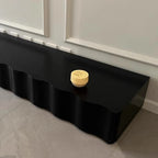 Black wavy shelf with a decorative item on a neutral background