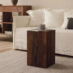 Wooden side table with a coffee cup on it, placed in front of a white sofa in a living room.