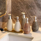 Set of five soap dispensers with different textures and finishes on a bathroom counter.