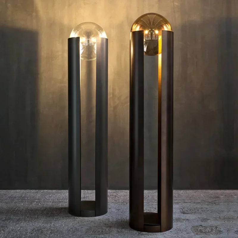 Two modern outdoor lamps with glass shades on a textured surface.