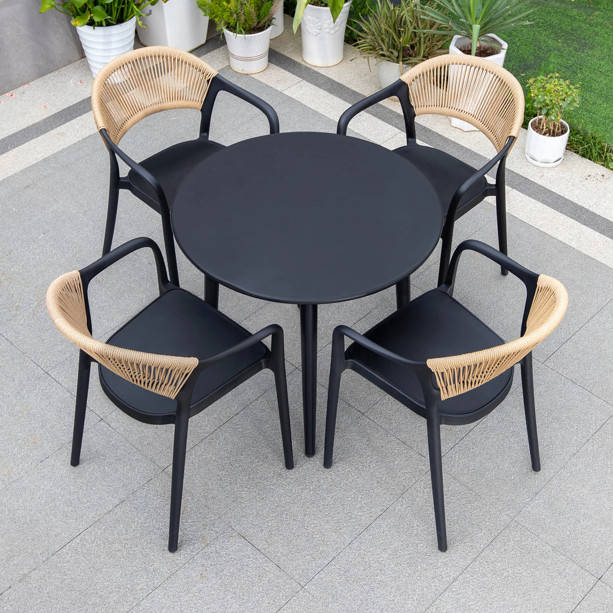 Black round table with four matching chairs featuring woven backrests on a tiled patio.
