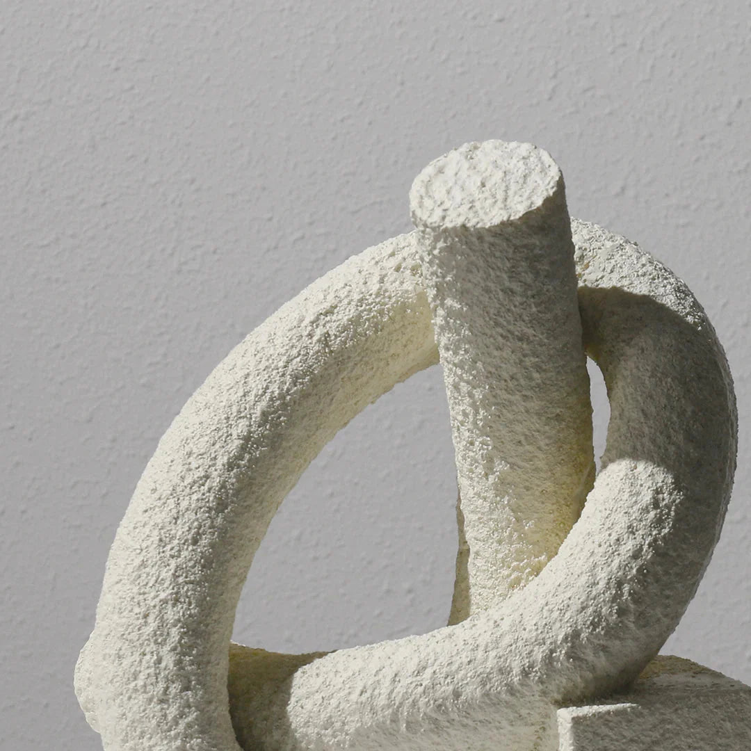 Abstract stone sculpture of intertwined loops on a gray background