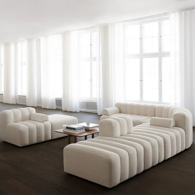 Modern beige sofa in a room with large windows and dark flooring