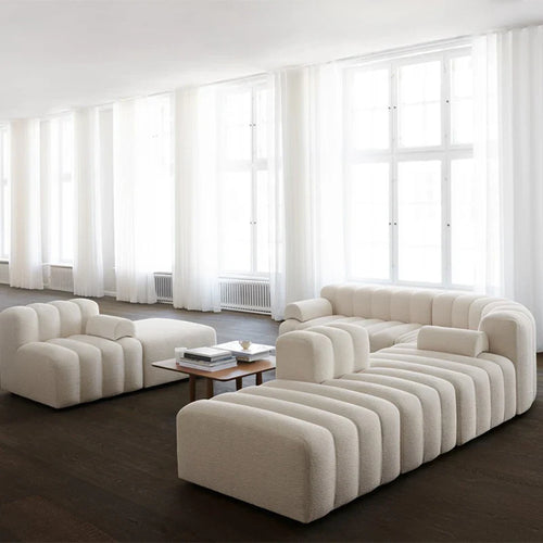 Modern beige sofa in a room with large windows and dark flooring