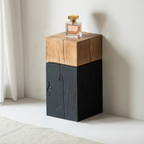Wooden and black side table with a perfume bottle on top