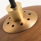 Close-up of a gold-colored metal object with a black handle on a wooden surface.