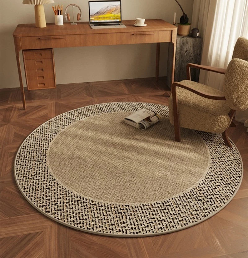 Round beige rug on a wooden floor with a desk and chair in the background