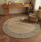 Round beige rug on a wooden floor with a desk and chair in the background