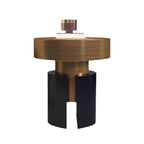A modern sculptural side table or lamp base with a brushed bronze circular top, a matching bronze cylindrical center, and a matte black split pedestal base, shown on a plain white background.