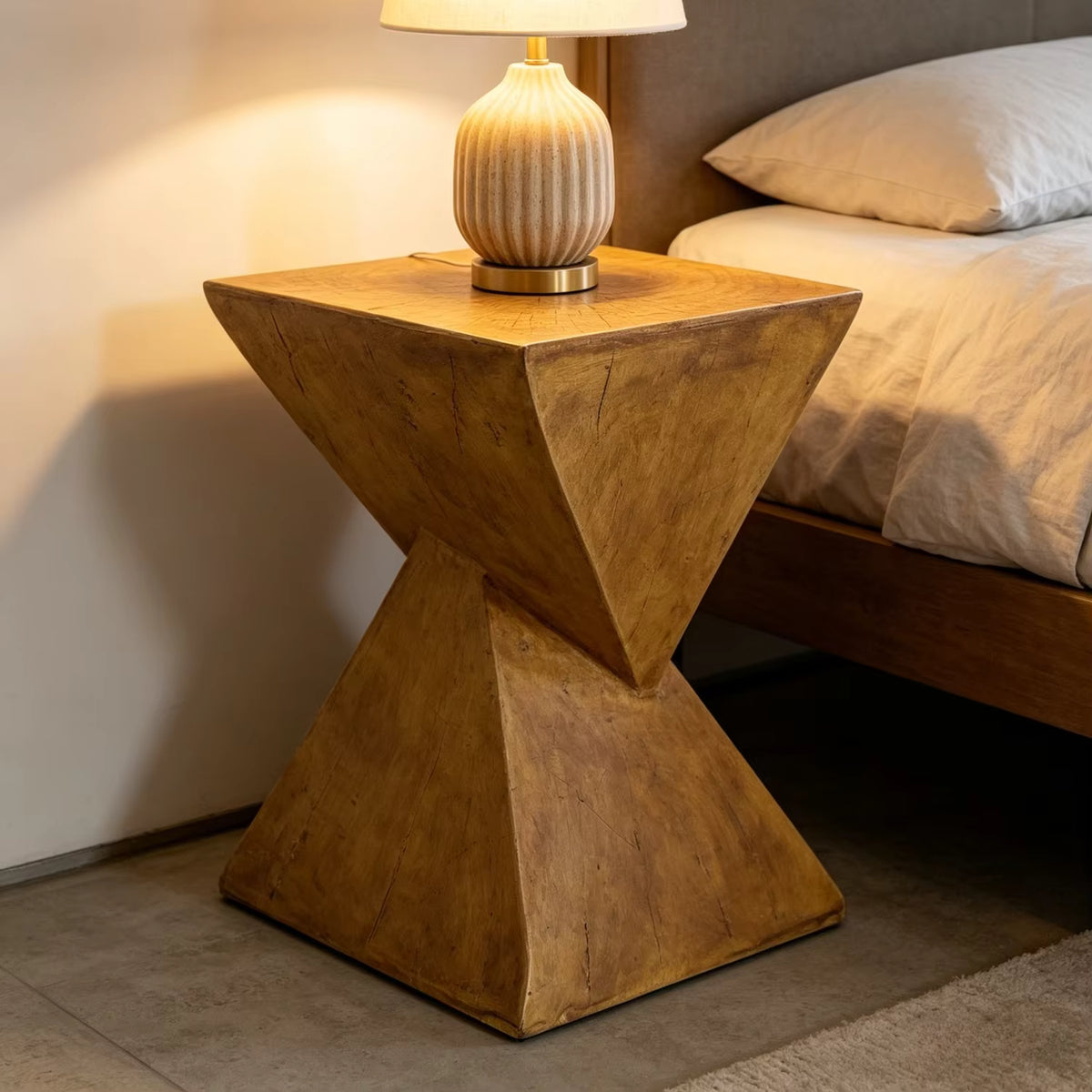 Concrete side table with a lamp next to a bed in a bedroom setting