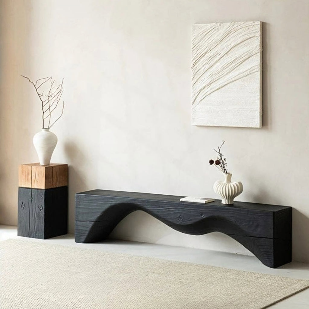 Modern black wavy console table with decorative items in a minimalistic room.