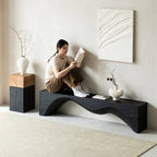 Woman reading a book on a modern black bench in a minimalistic room.