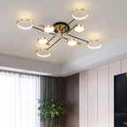Modern ceiling light fixture with six circular LED rings and a central gold-toned hub, mounted on a white ceiling in a contemporary room.
