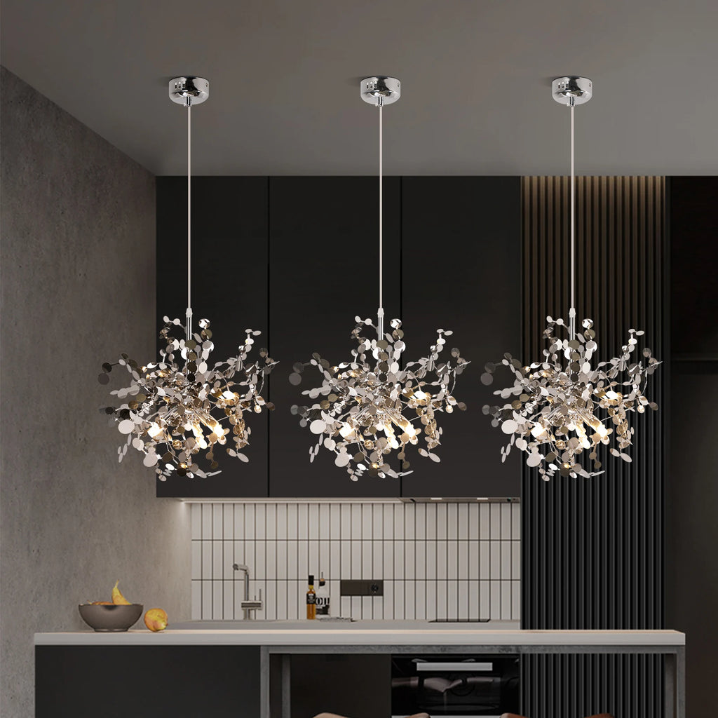 Three modern chandelier lights hanging above a kitchen counter with a dark wall and tiled backsplash in the background.