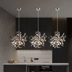 Three modern chandelier lights hanging above a kitchen counter with a dark wall and tiled backsplash in the background.