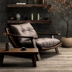 Modern lounge chair with wooden armrests and a coffee table in a room with dark walls and decorative elements.