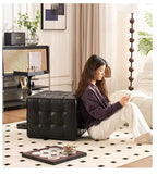 Woman sitting on a black cube-shaped ottoman in a stylish living room.