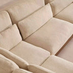 Beige textured fabric sectional sofa with multiple plush seat and back cushions, shown in a close-up interior view.