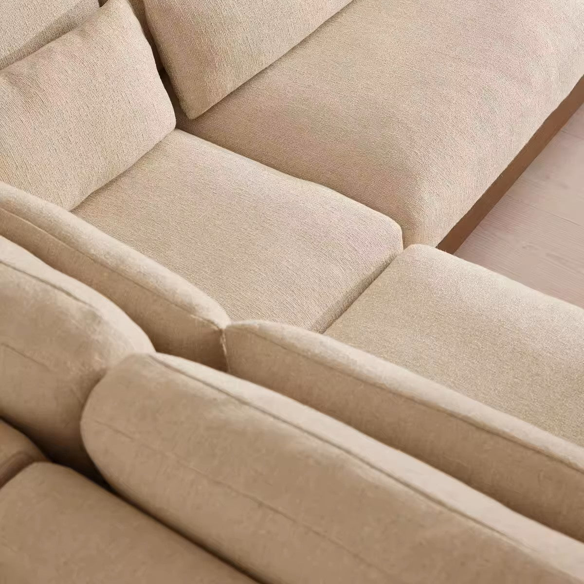 Close-up of a beige upholstered sectional sofa showing the textured fabric and clean lines of the cushions.