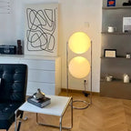 Modern living room with a black leather chair, white table, and floor lamp.