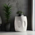 White textured side table with plants against a gray wall