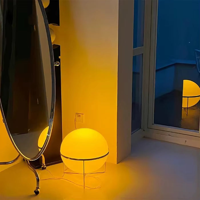 Yellow spherical lamp on a stand in a room with a mirror and window.