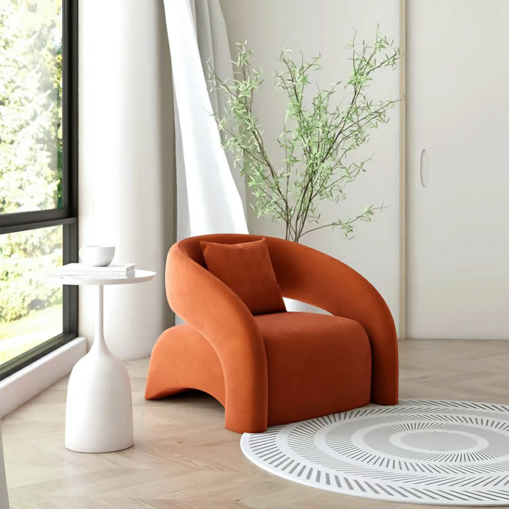 Orange armchair in a modern room with a window, side table, and plant.