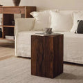Wooden side table with a coffee cup on it, placed in front of a white sofa in a living room setting.