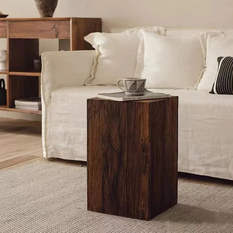 Wooden side table with a coffee cup on it, placed in front of a white sofa in a living room setting.