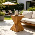 Concrete  side table with a bucket of ice and wine glass on a patio with outdoor furniture and umbrella.