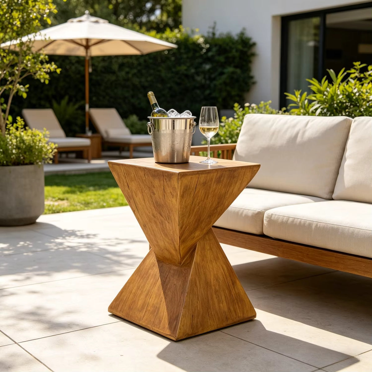 Concrete  side table with a bucket of ice and wine glass on a patio with outdoor furniture and umbrella.