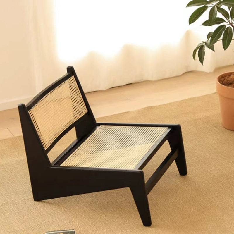 Black pet bed with wicker design on a beige carpet