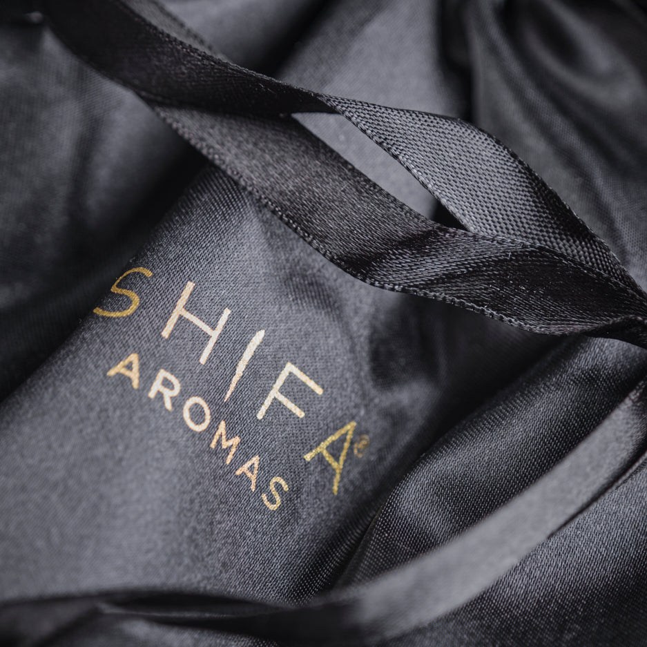 Black drawstring bag with 'Shifa Aromas' logo on a dark background