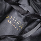 Black drawstring bag with 'Shifa Aromas' logo on a dark background