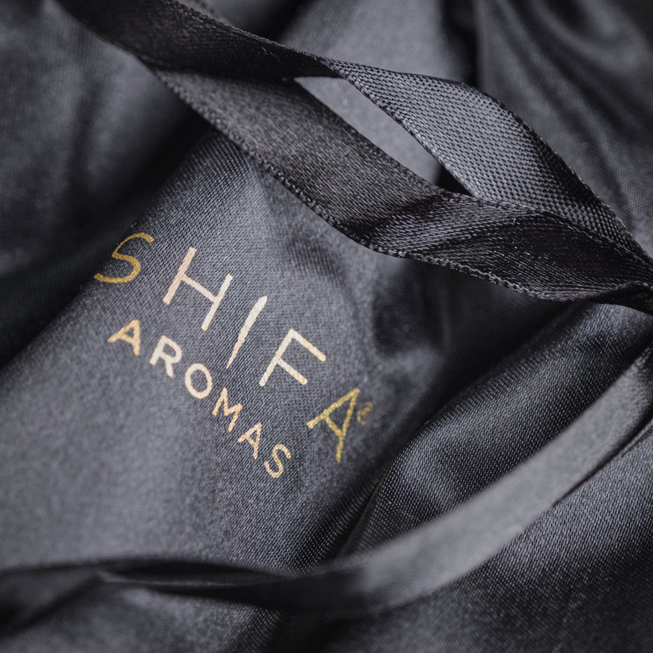 Black drawstring bag with 'Shifa Aromas' logo on a dark background