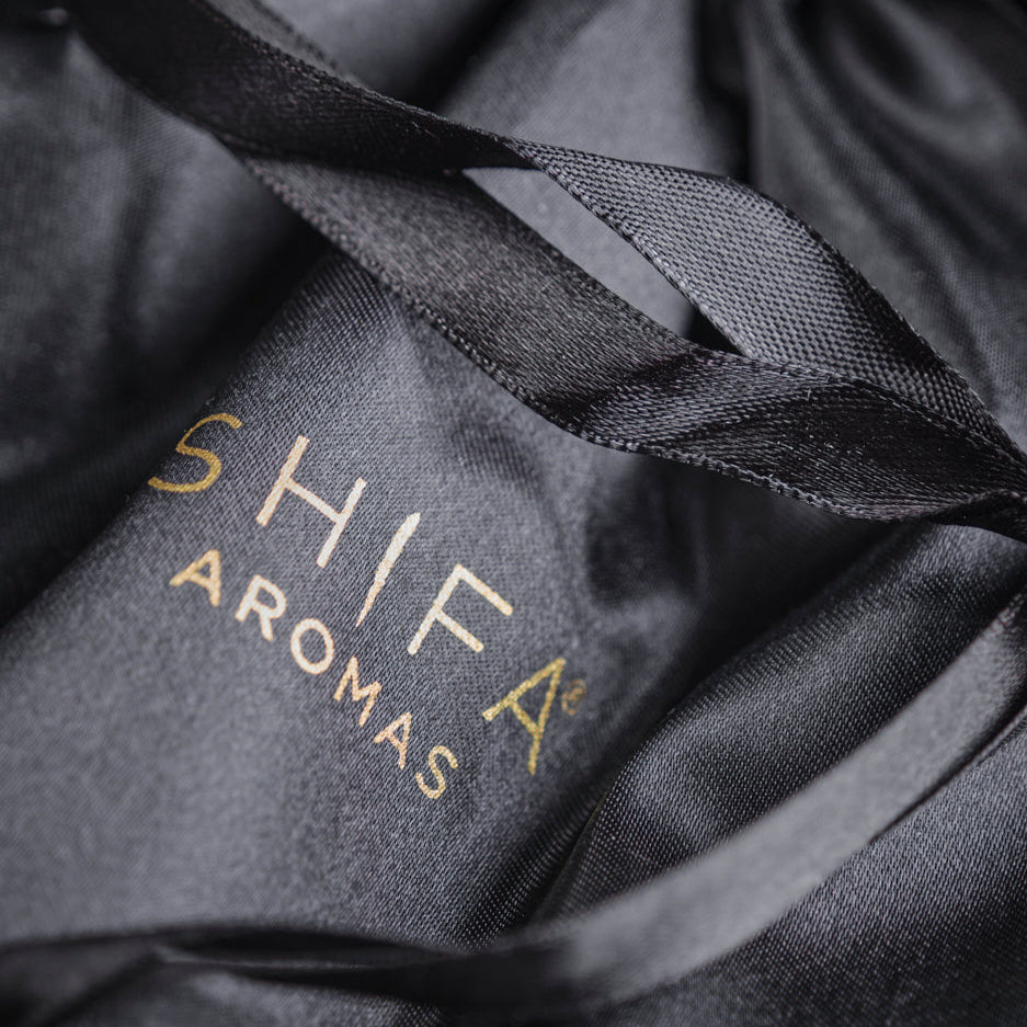 Black drawstring bag with 'Shifa Aromas' branding on a dark background