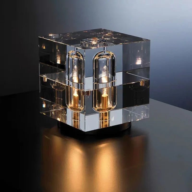Modern glass cube table lamp with multiple light bulbs on a dark surface.