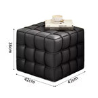 Black cube-shaped ottoman with dimensions and a book on top