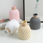 Set of four textured vases in pink, white, beige, and gray on a light surface.