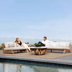 Two people sitting on outdoor furniture by a pool with a clear blue sky.