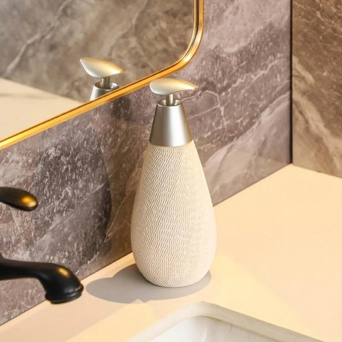 Beige textured soap dispenser on a bathroom counter with marble wall in the background